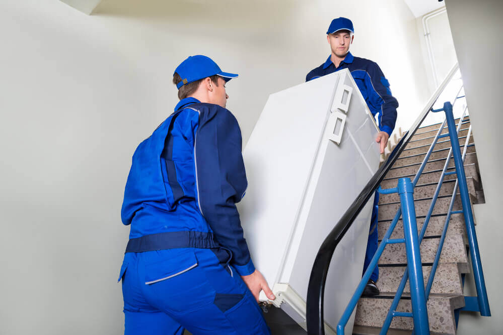 Nashville Movers carrying a fridge down to the first floor.