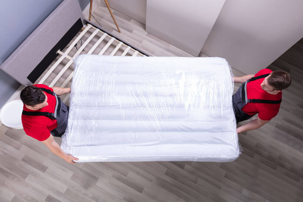 Mover in Denver carrying a white bed.