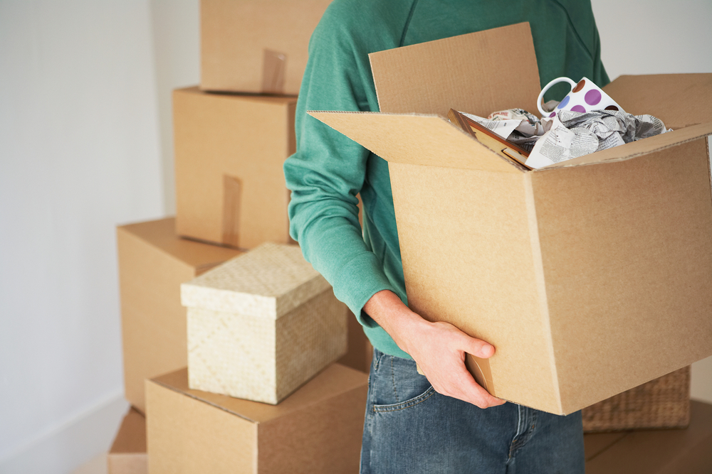 A guy carrying a box with Auburn Movers.