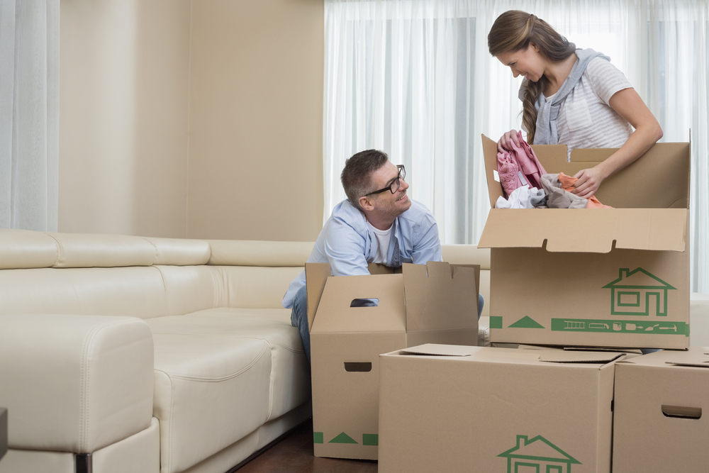 Happy couple unpacking cardboard boxes in new home
