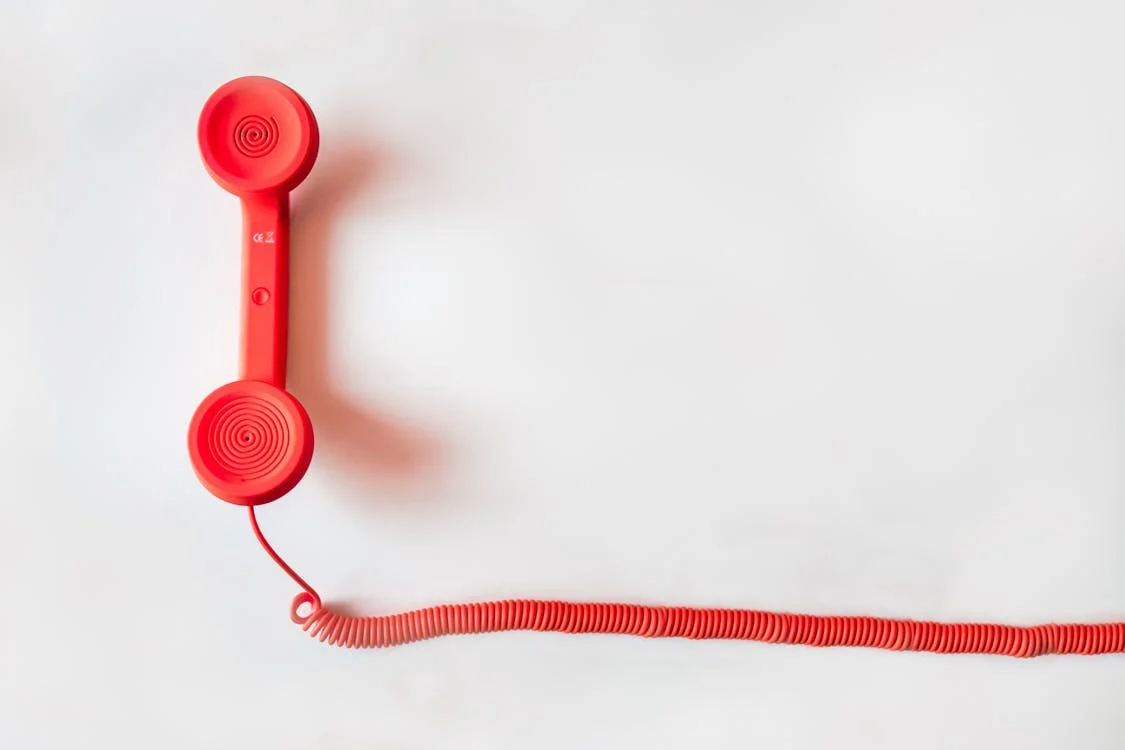 Red telephone on a white surface.  