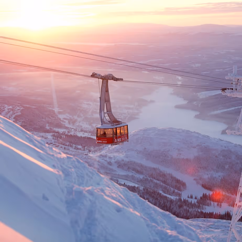 En skidlift silhuetterad mot en dramatisk solnedgångshimmel med varma, orange och röda färgnyanser