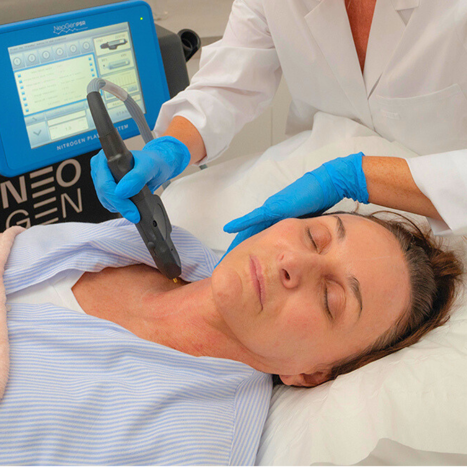 Woman receiving a neck treatment with a handheld device by a professional wearing blue gloves and a white coat.