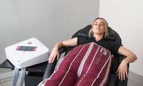 A woman receiving a facial treatment with a handheld device from a professional wearing gloves in a spa clinic.