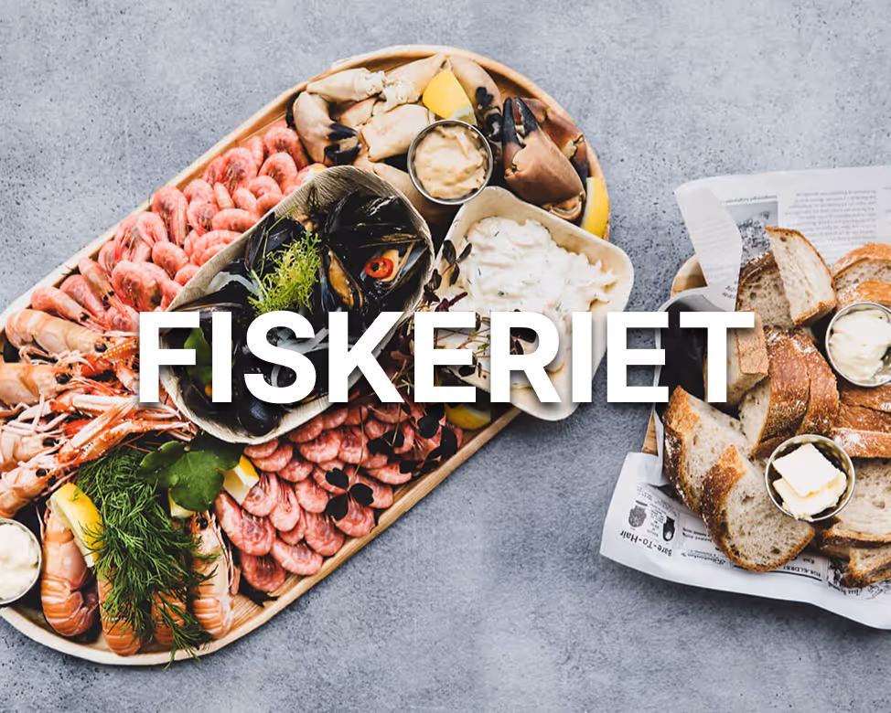 Fat med assortert skalldyr, inkludert reker, krabbeklør og blåskjell, med sitron og dip, ved siden av tallerken med brød og smør.