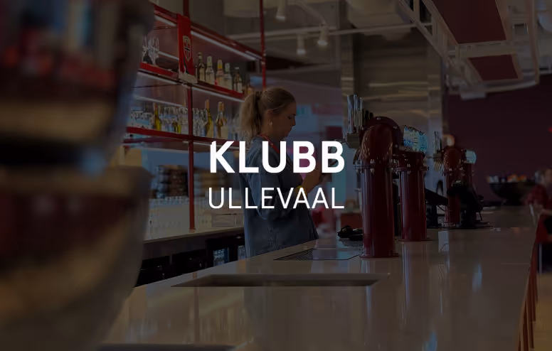 En kvinne står bak bardisken i en bar med flere øltapper på disken.