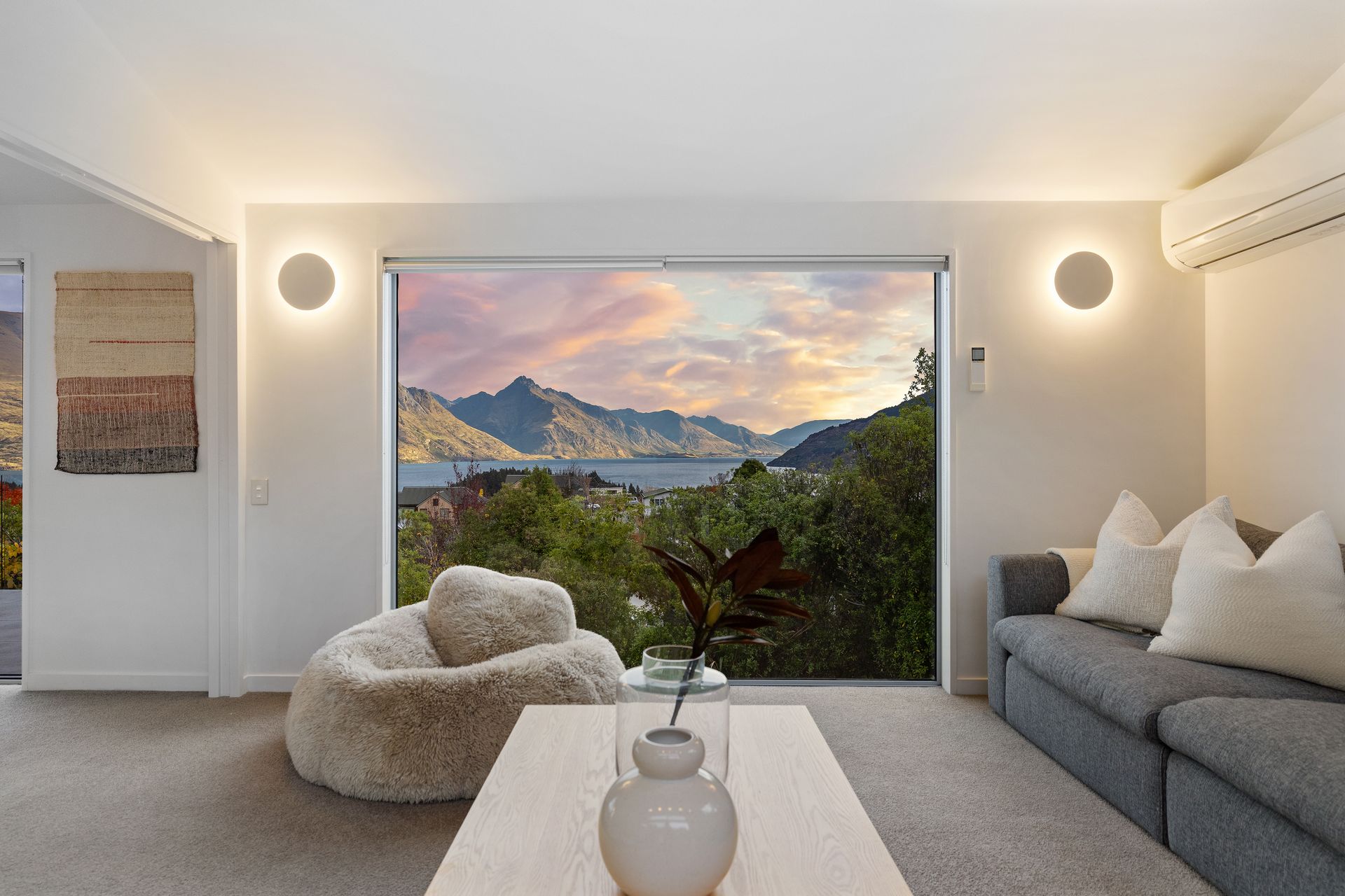 Living room at Hillside Haven Queenstown with picture-window views over Lake Whakatipu at sunset