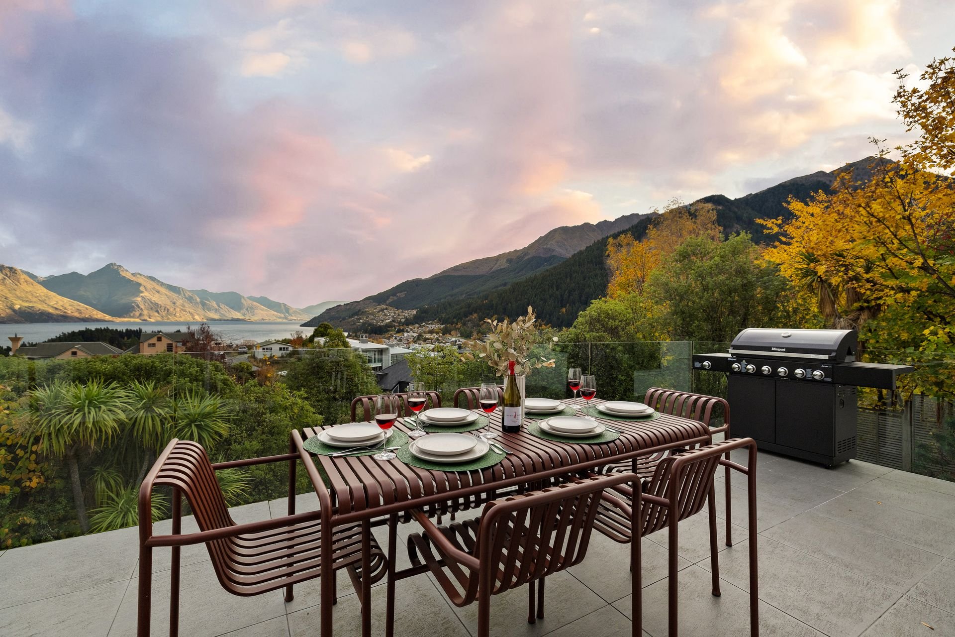 Balcony dining table and BBQ at Hillside Haven Queenstown with lake and mountain views