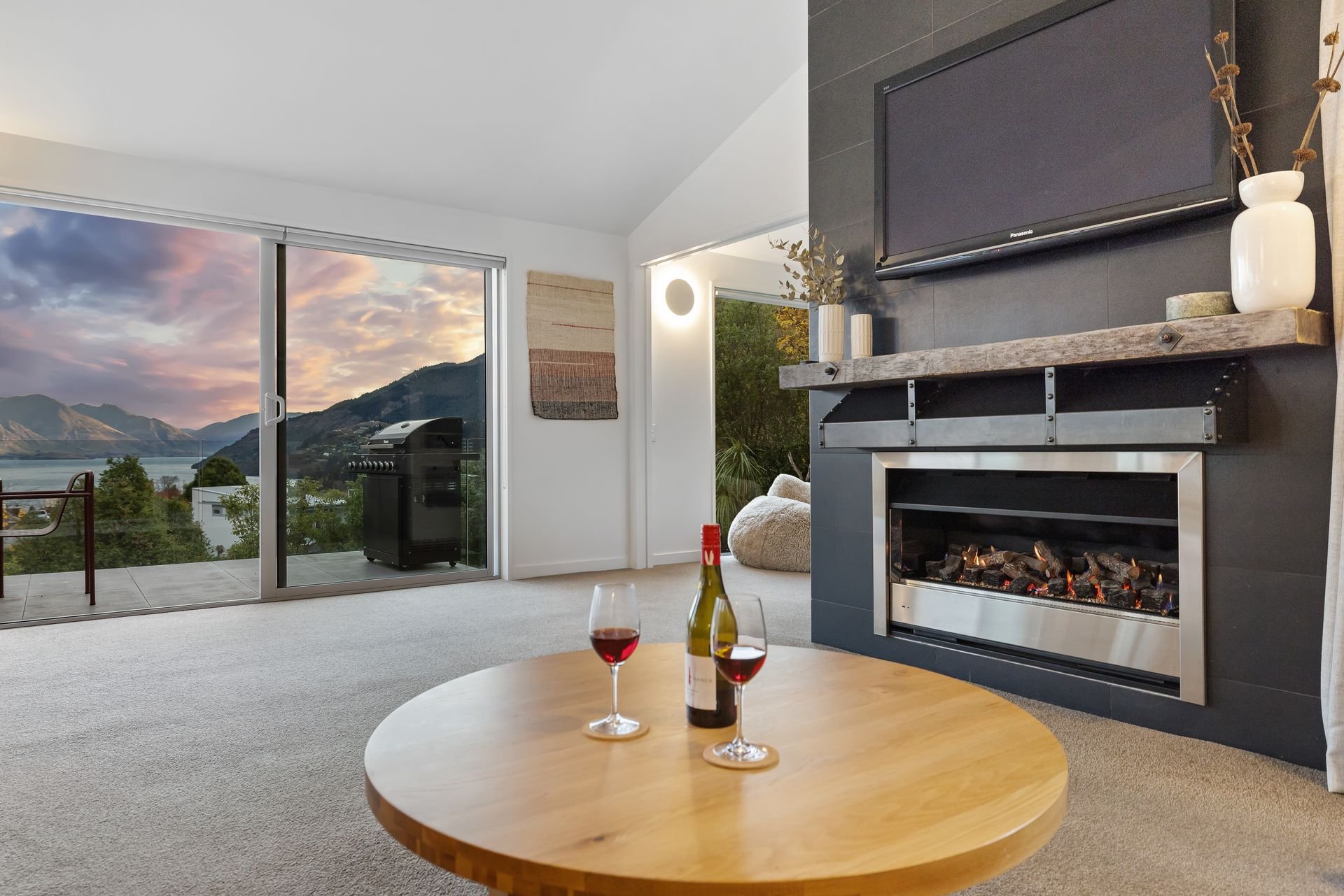 Fireplace and balcony with BBQ and lake views at Hillside Haven Queenstown
