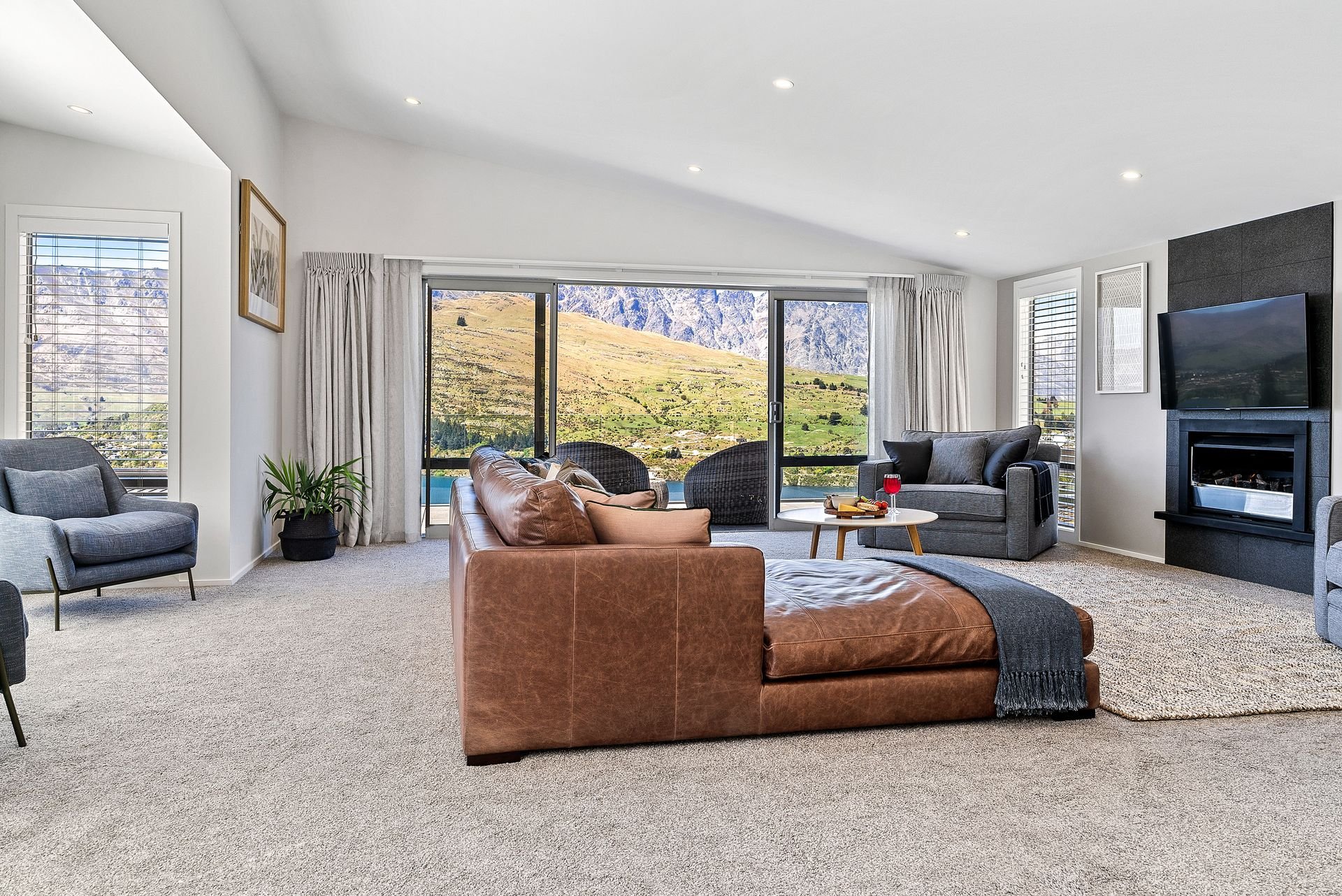 Open-plan living area with leather sofa and mountain views at Highview Haven, Queenstown