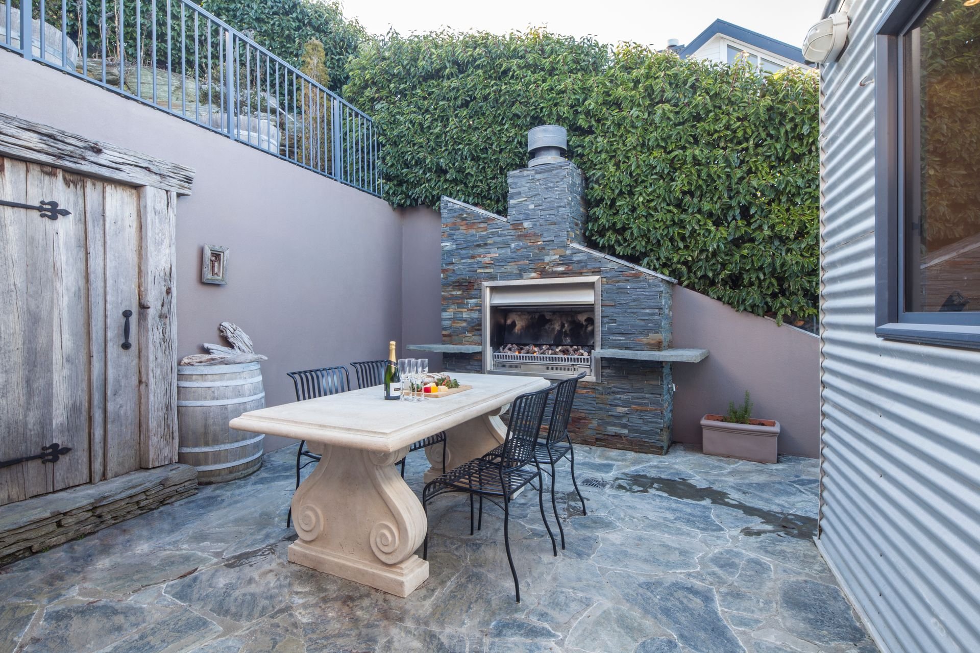 Courtyard with outdoor fireplace and dining table at Edinburgh Heights, Queenstown