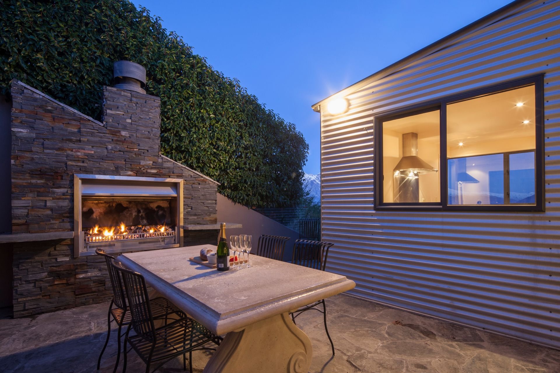 Outdoor fireplace lit at dusk in the courtyard at Edinburgh Heights, Queenstown