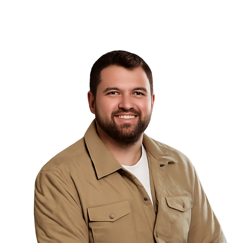 Smiling man with short dark hair and beard wearing a tan jacket over a white shirt against a dark gradient background.
