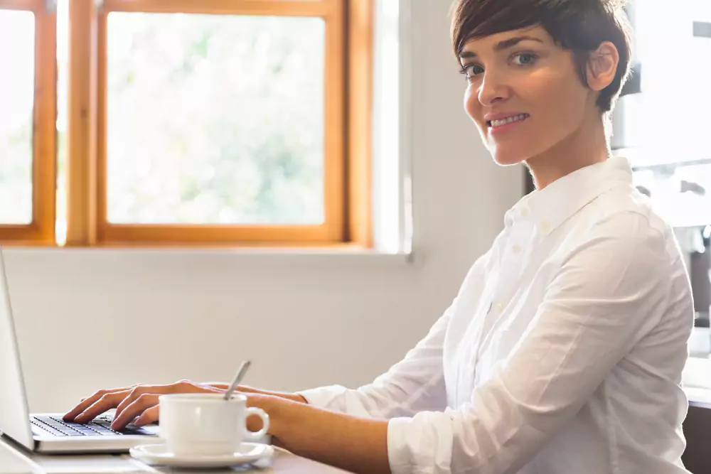 Mujer usando un laptop con un café