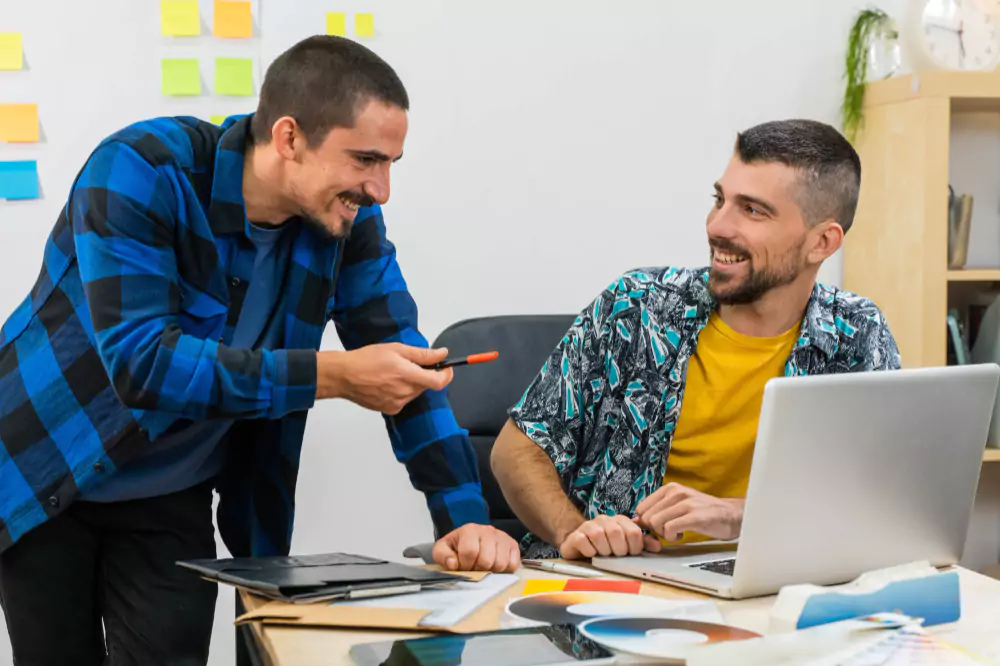 Dos jóvenes socios de negocios sonriendo mientras trabajan en la oficina
