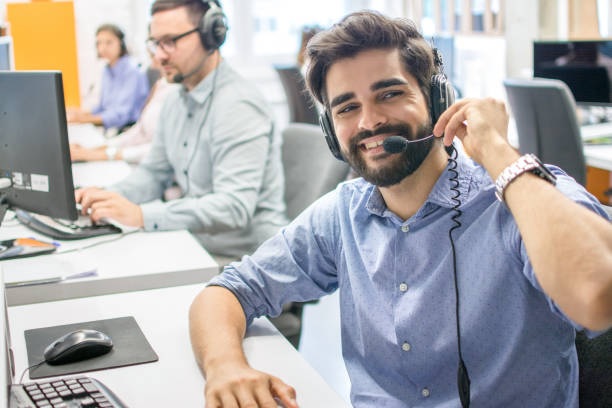 Operador de atención al cliente masculino amigable con auriculares trabajando en un centro de llamadas
