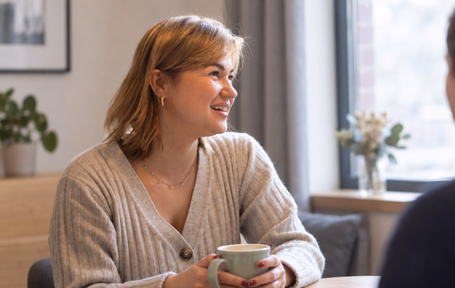 Frau mit einer Tasse im Gespräch im Büro.