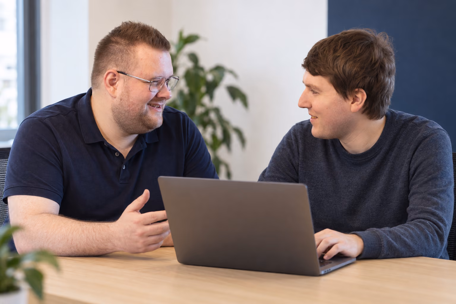 Zwei Teammitglieder besprechen ihre Arbeit an einem Laptop.