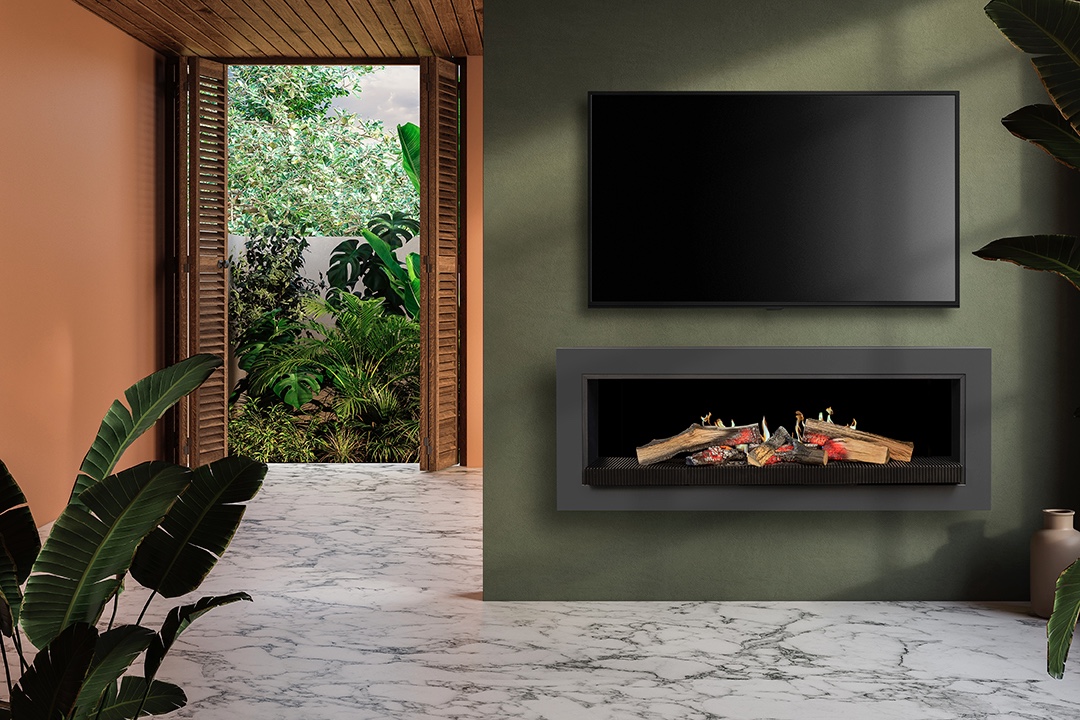 Modern interior living space with a wall-mounted flat-screen TV above a built-in electric fireplace featuring realistic glowing logs and ember effects. The room has a minimalist aesthetic with a green accent wall, orange side wall, white marble flooring, and tropical plants including bird of paradise and monstera. Wooden louvered double doors open to a lush, green garden filled with dense foliage and sunlight filtering through trees. The space blends indoor luxury with natural outdoor elements, showcasing biophilic design, eco-friendly decor, and contemporary home styling.