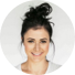 Portrait d'une femme souriante avec les cheveux attachés en chignon, portant un t-shirt gris.