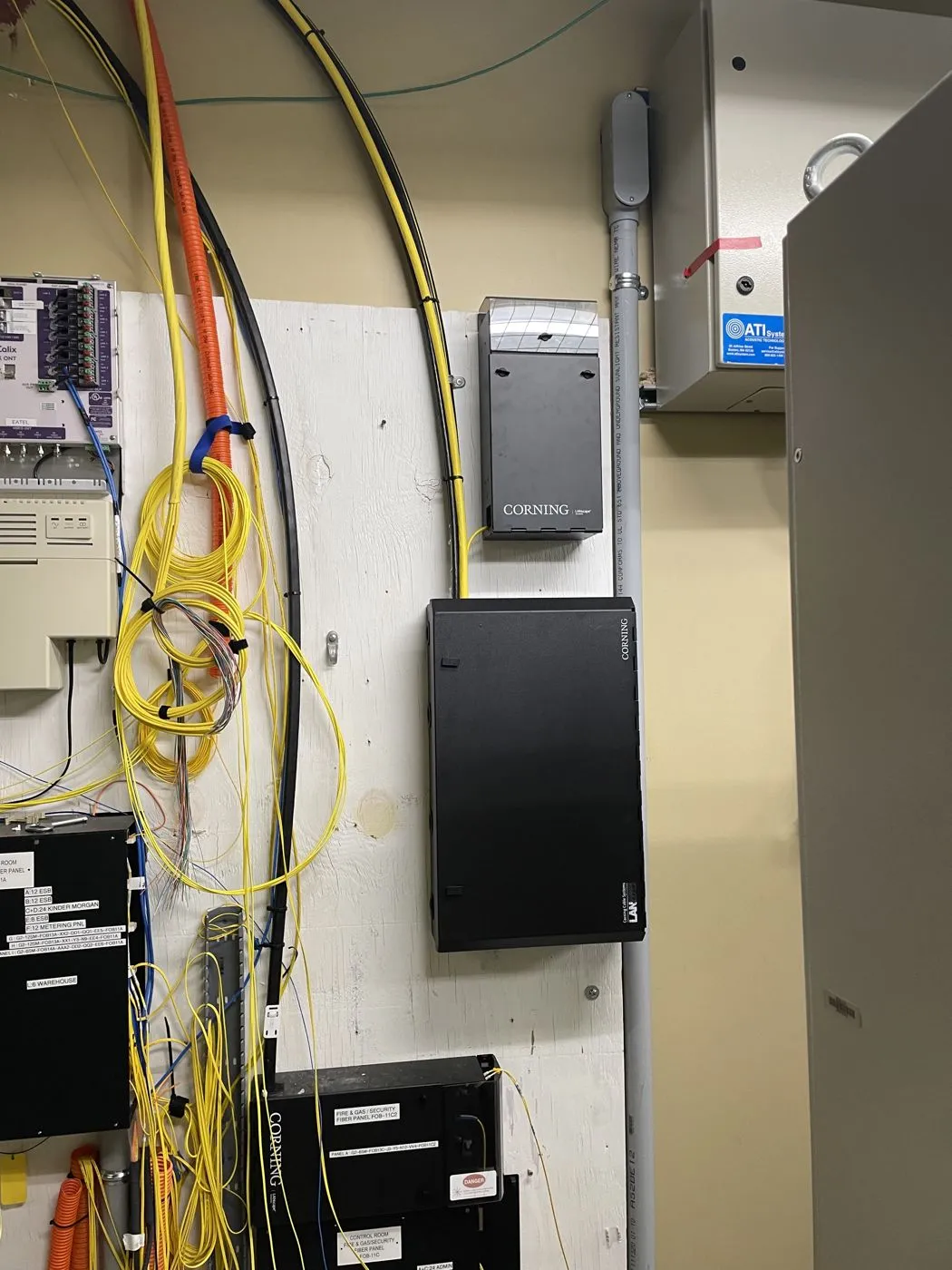 Fiber optic cabling and Corning fiber enclosures on a telecom backboard