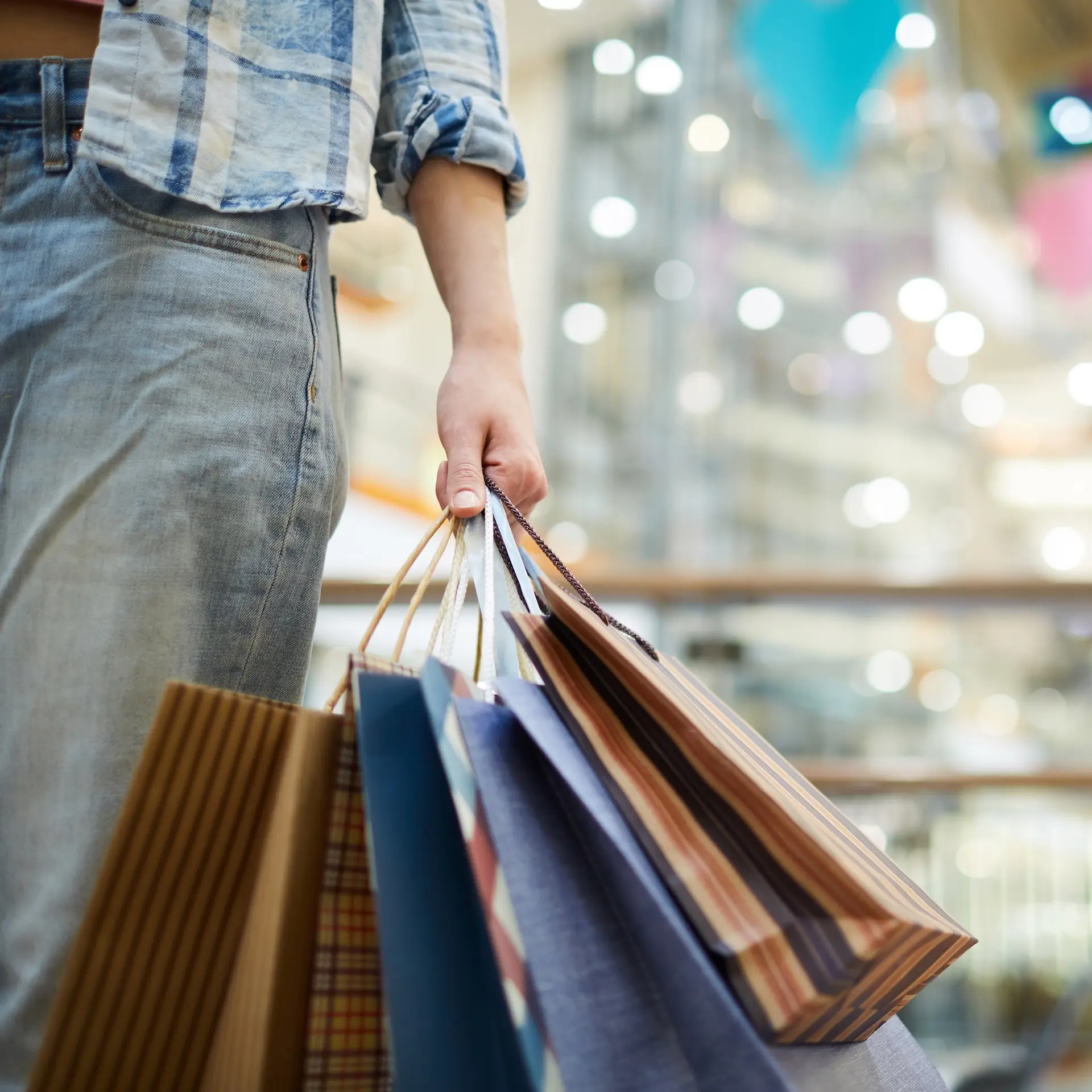 a shopper is leaving a mall with several colorful bags in hand