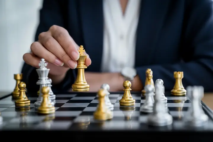 a business woman makes a chess move with a golden piece