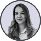 Portrait of a woman with long, wavy hair wearing a white shirt and a blazer, smiling slightly.
