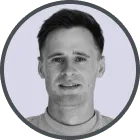 Portrait of a young man with short dark hair and a neutral expression against a light background.