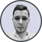 Black and white headshot of a young man with short hair and a trimmed beard, wearing a collared shirt.