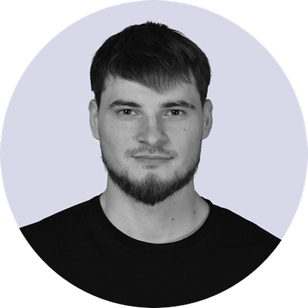 Headshot of a young man with short dark hair, a trimmed beard, and wearing a black shirt against a light background.