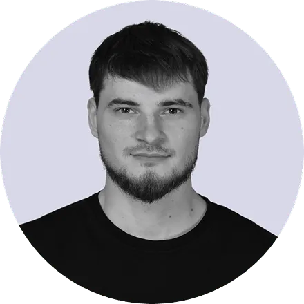 Headshot of a young man with short dark hair, a trimmed beard, and wearing a black shirt against a light background.
