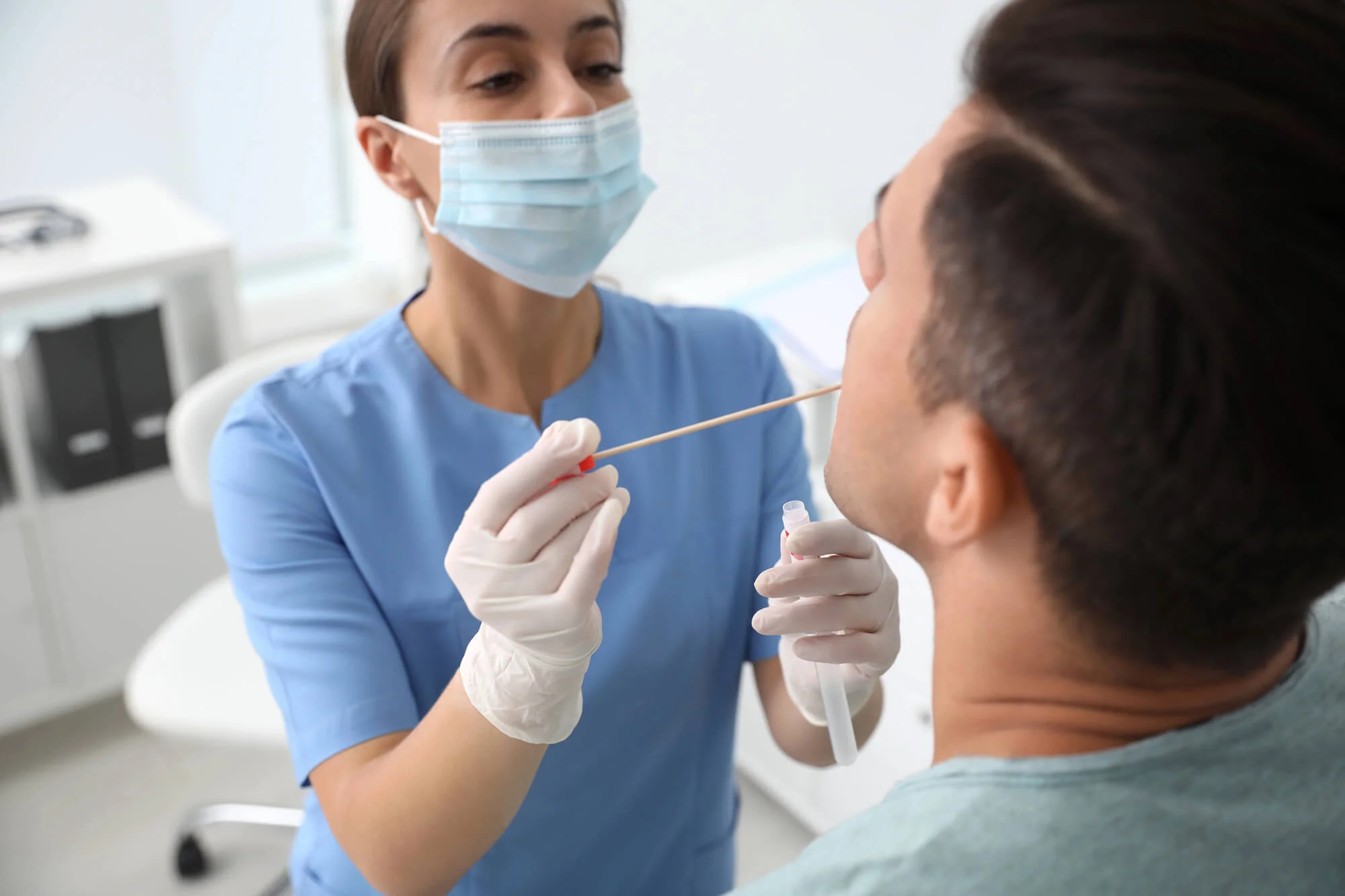 Dental professional performing oral DNA testing in Virginia by taking cheek swab from male patient