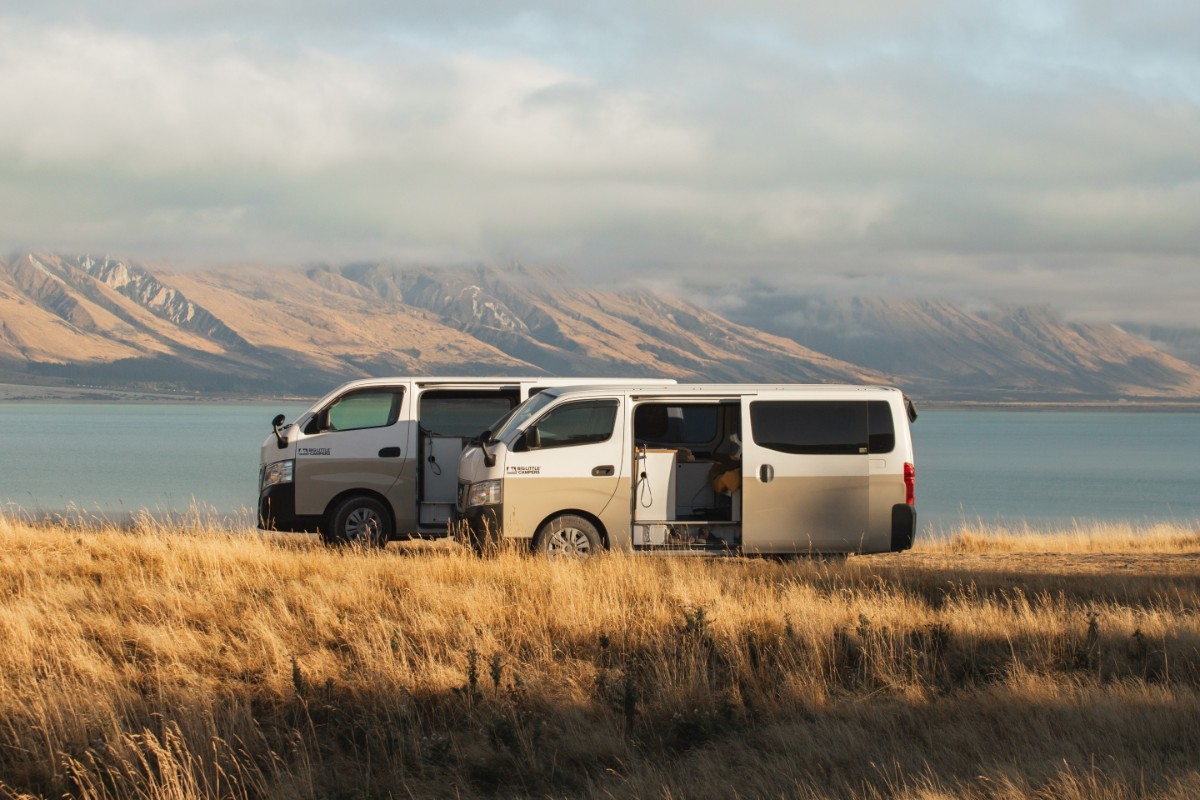 Two Big Little Campers vans parked beside a lake in the Mackenzie