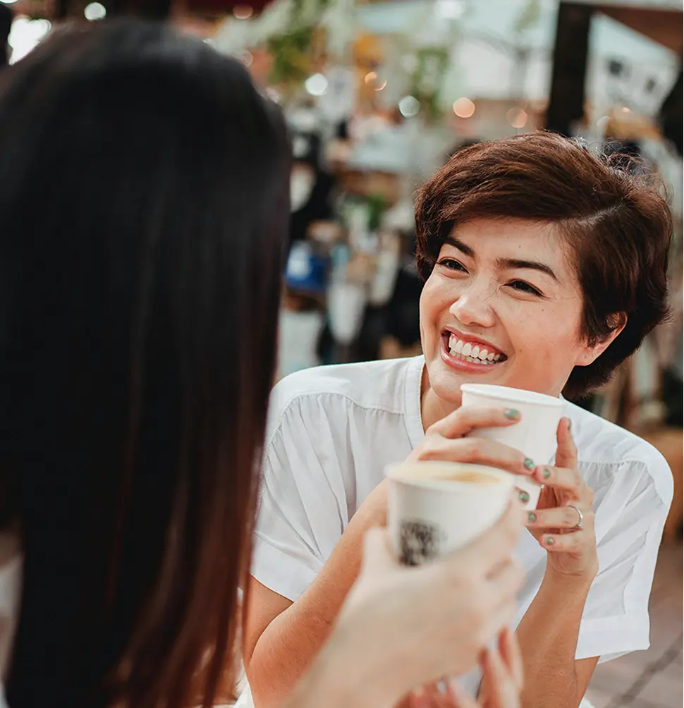 A woman sitting at a table with a cup of coffee.