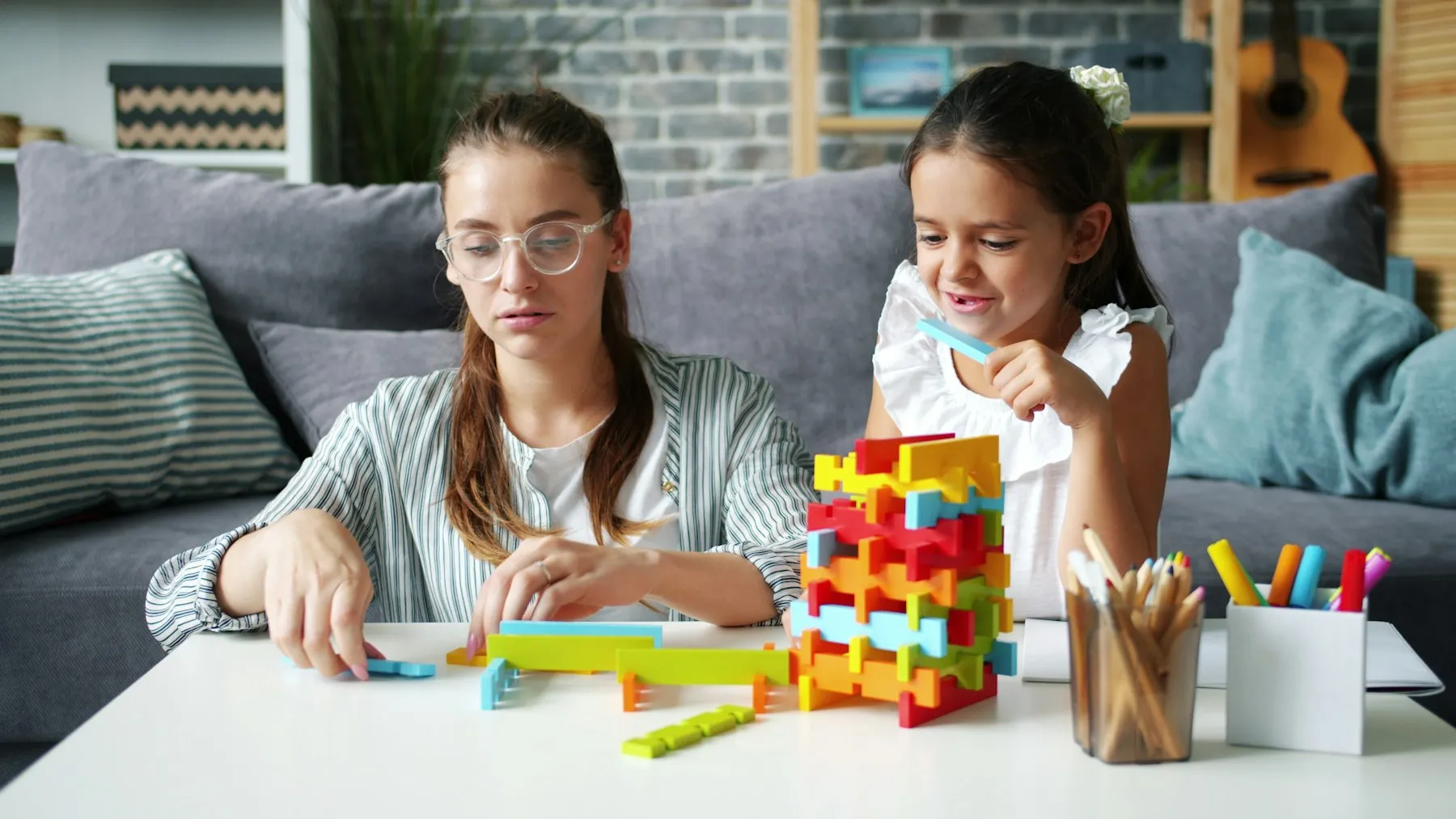 An adult and school-age child building and drawing together at home.