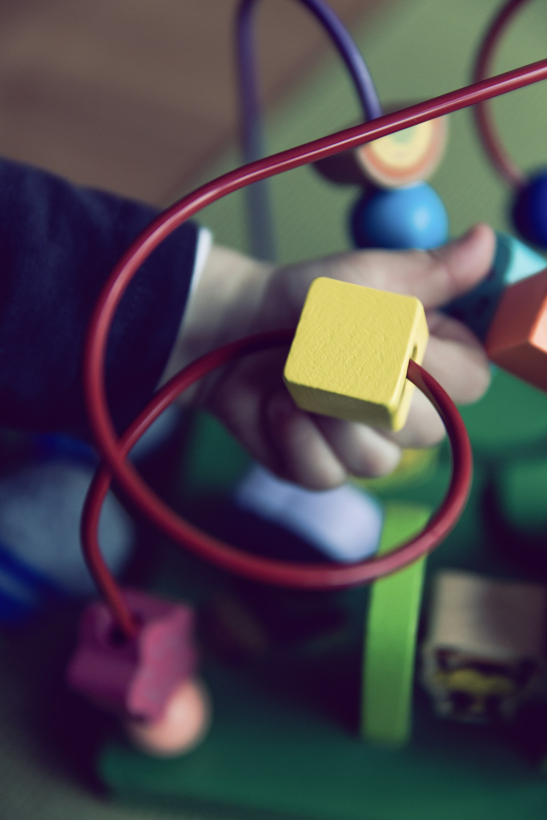 A young child fully absorbed in sorting colorful wooden shapes at our Early Learner Center.