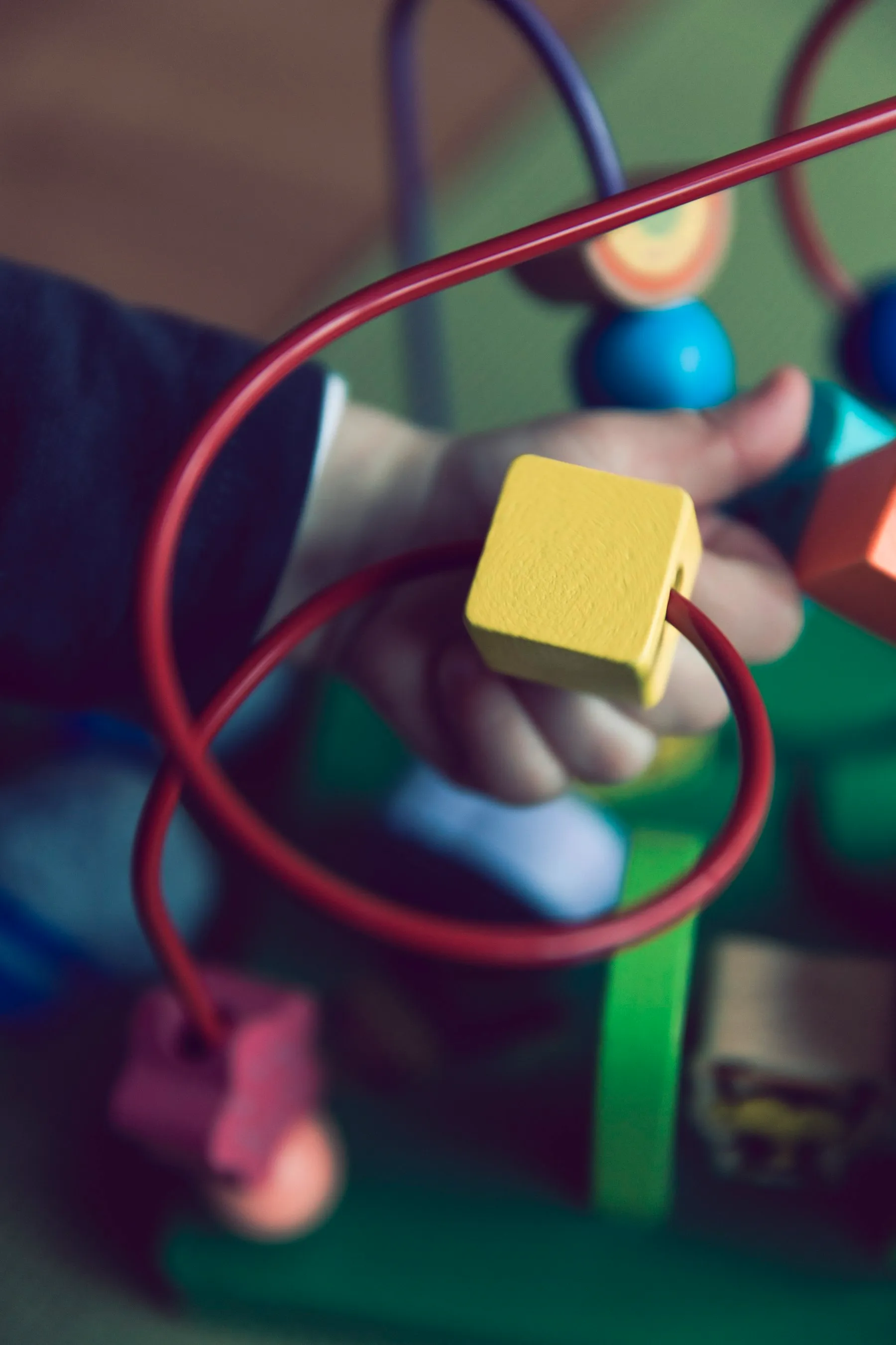 A young child fully absorbed in sorting colorful wooden shapes at our Early Learner Center.
