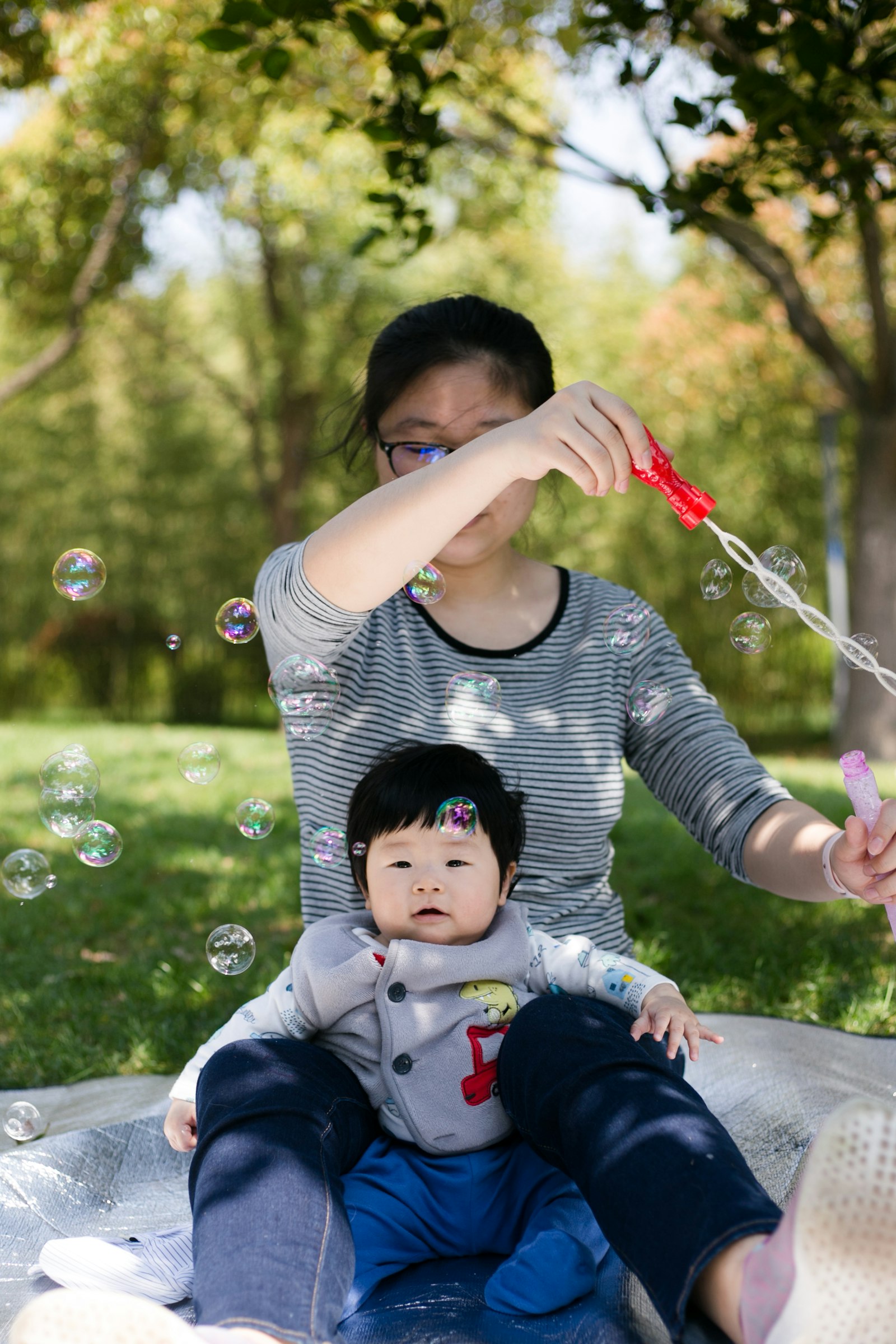 Un padre y su bebé jugando con burbujas en el césped.
