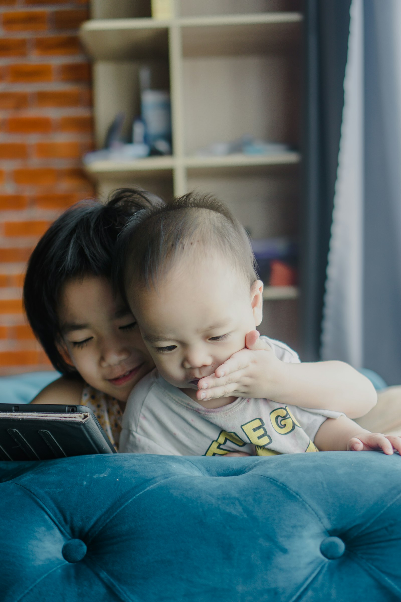 Dos niños mirando juntos una tableta en el sofá.