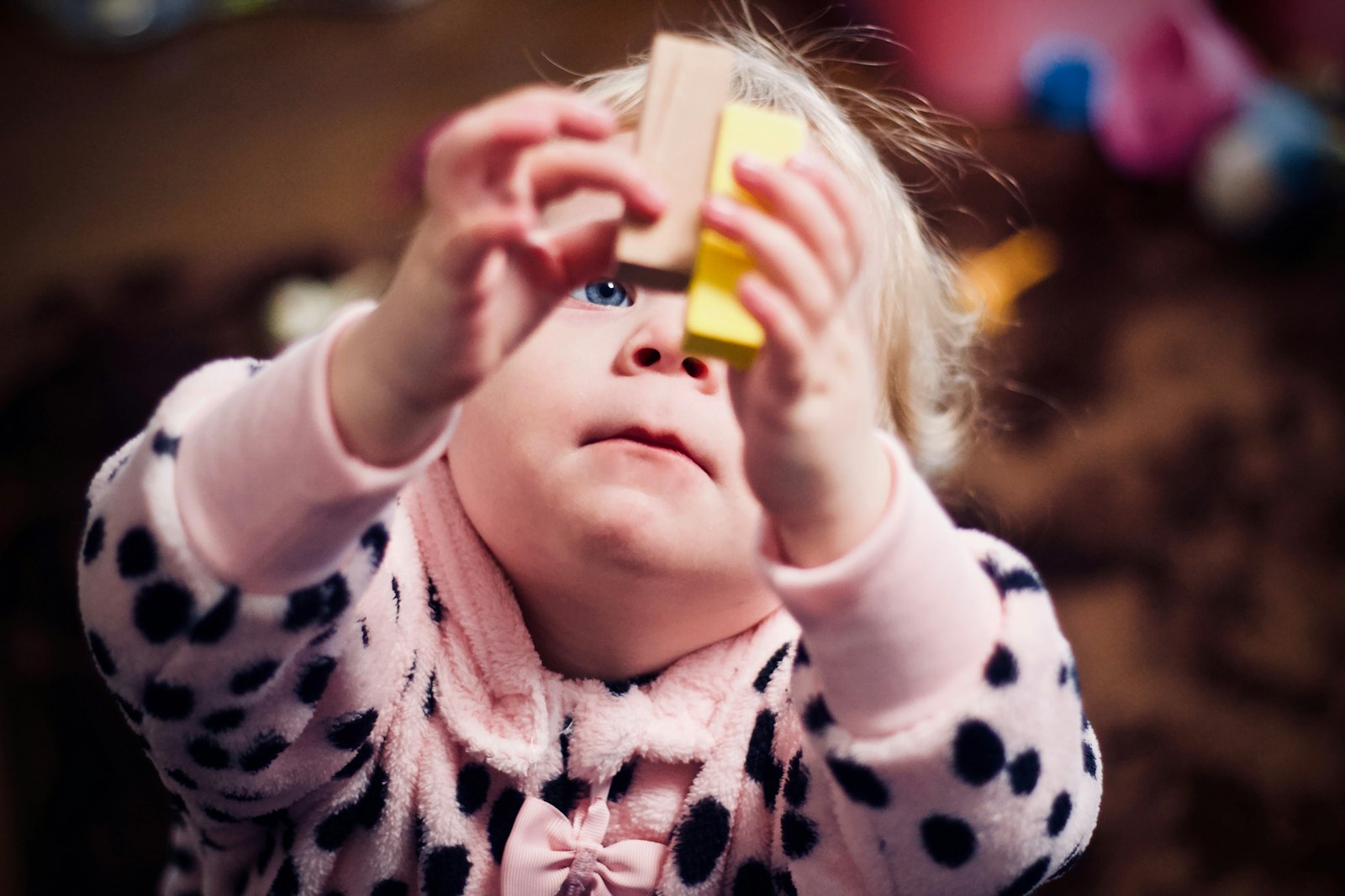 A toddler exploring a wooden block during play.