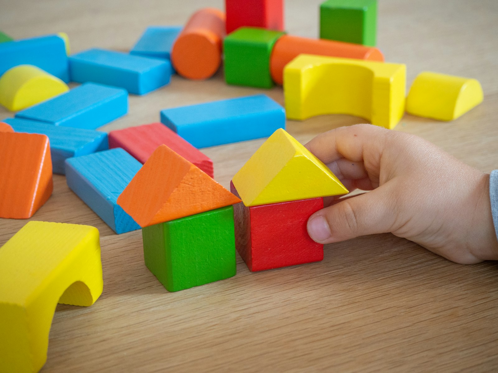 A child building with brightly colored wooden blocks.