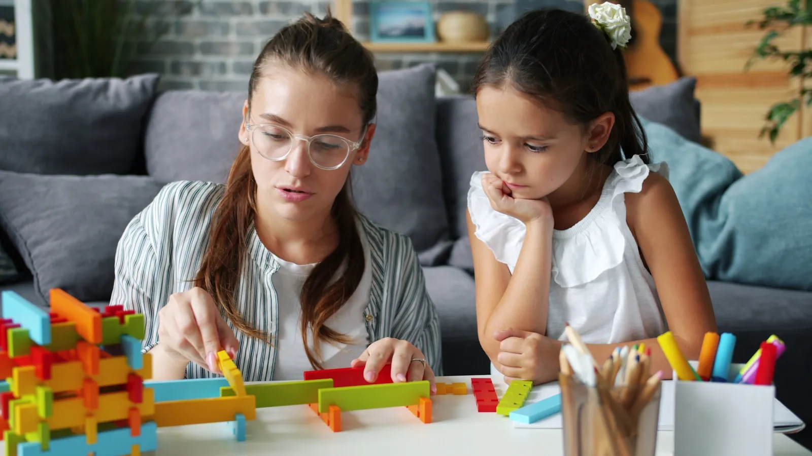 A clinician and a young child building with colorful blocks together during a learning activity.