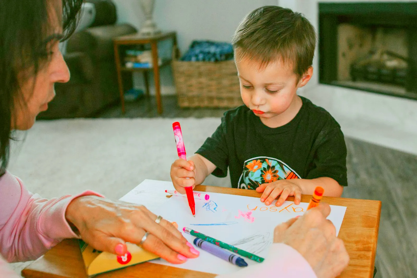 A care professional helping a young child with a learning activity at a table.
