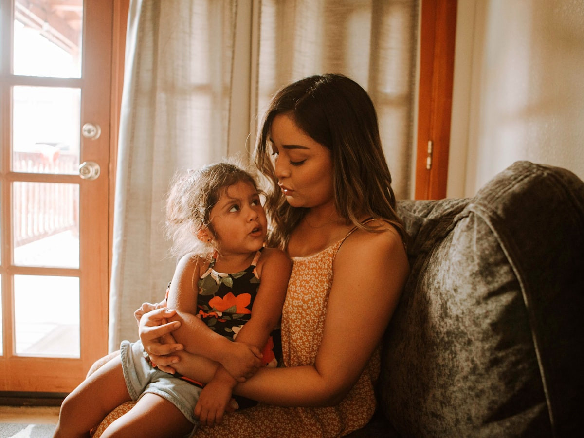 A mother holding her young daughter close at home.