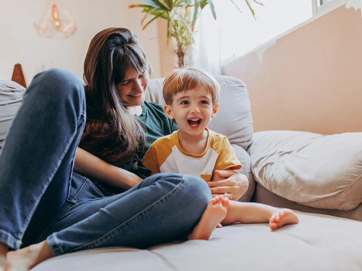 A mother and her young son laughing together at home.