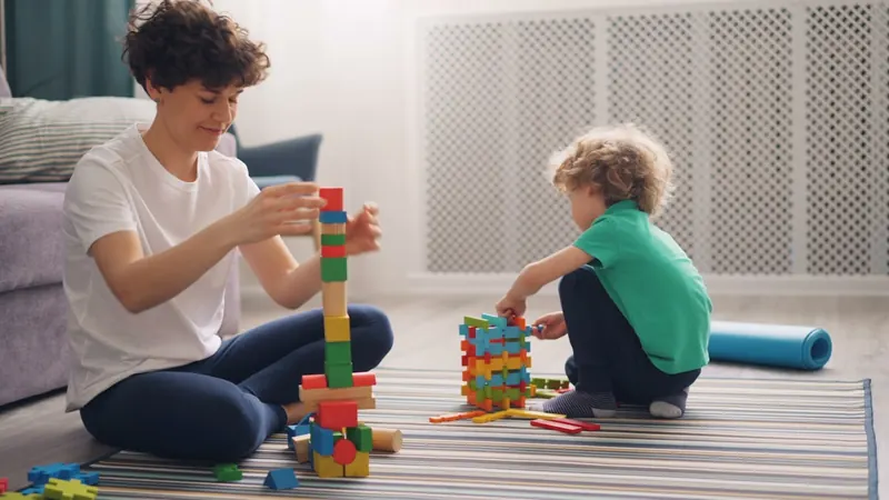 Illustrative stock photo of an adult and young child building with colorful blocks together.
