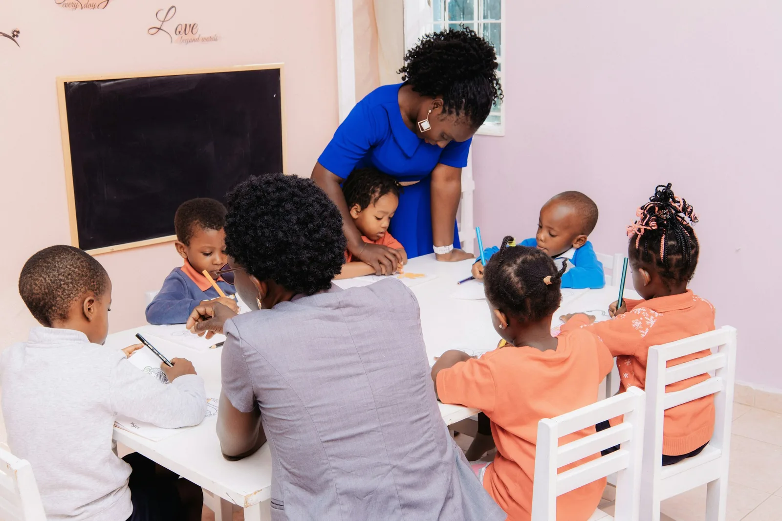Representative scene of an adult supporting a small group activity at a table.