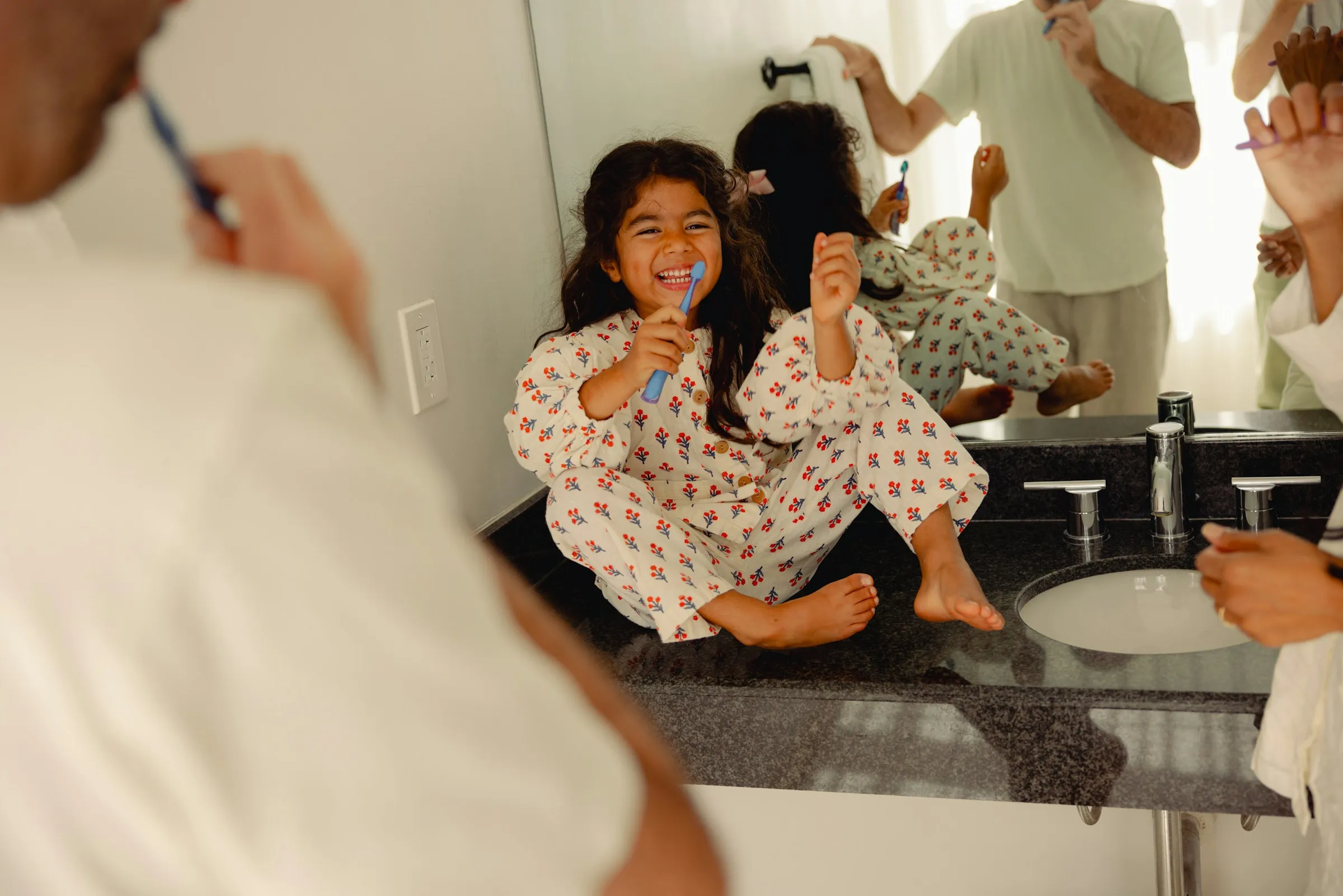 A family brushes their teeth together at the bathroom sink.