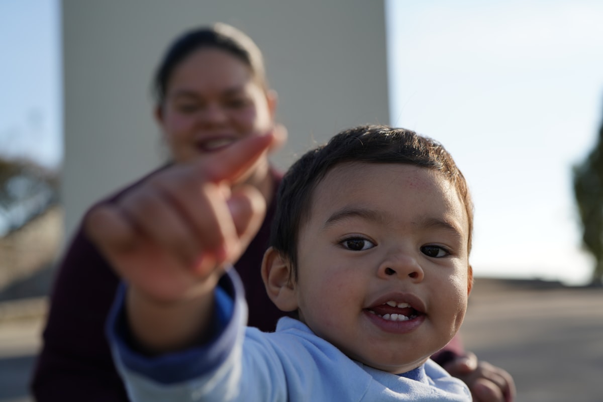 A young child pointing while a parent looks on, communicating with a gesture.
